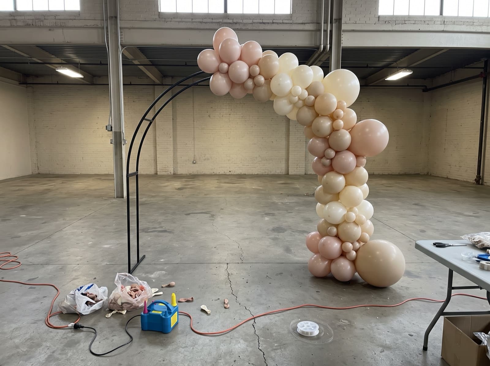 Organic balloon garland half-built on an arch frame before an event
