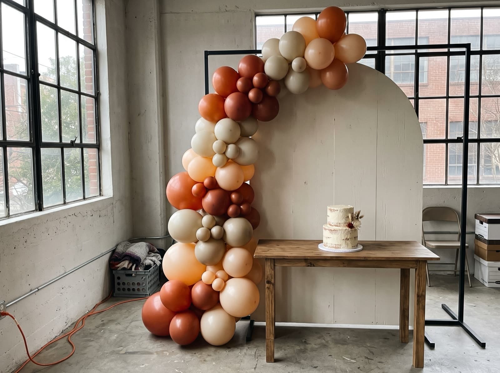 Half balloon arch in burnt orange and cream over a cake table