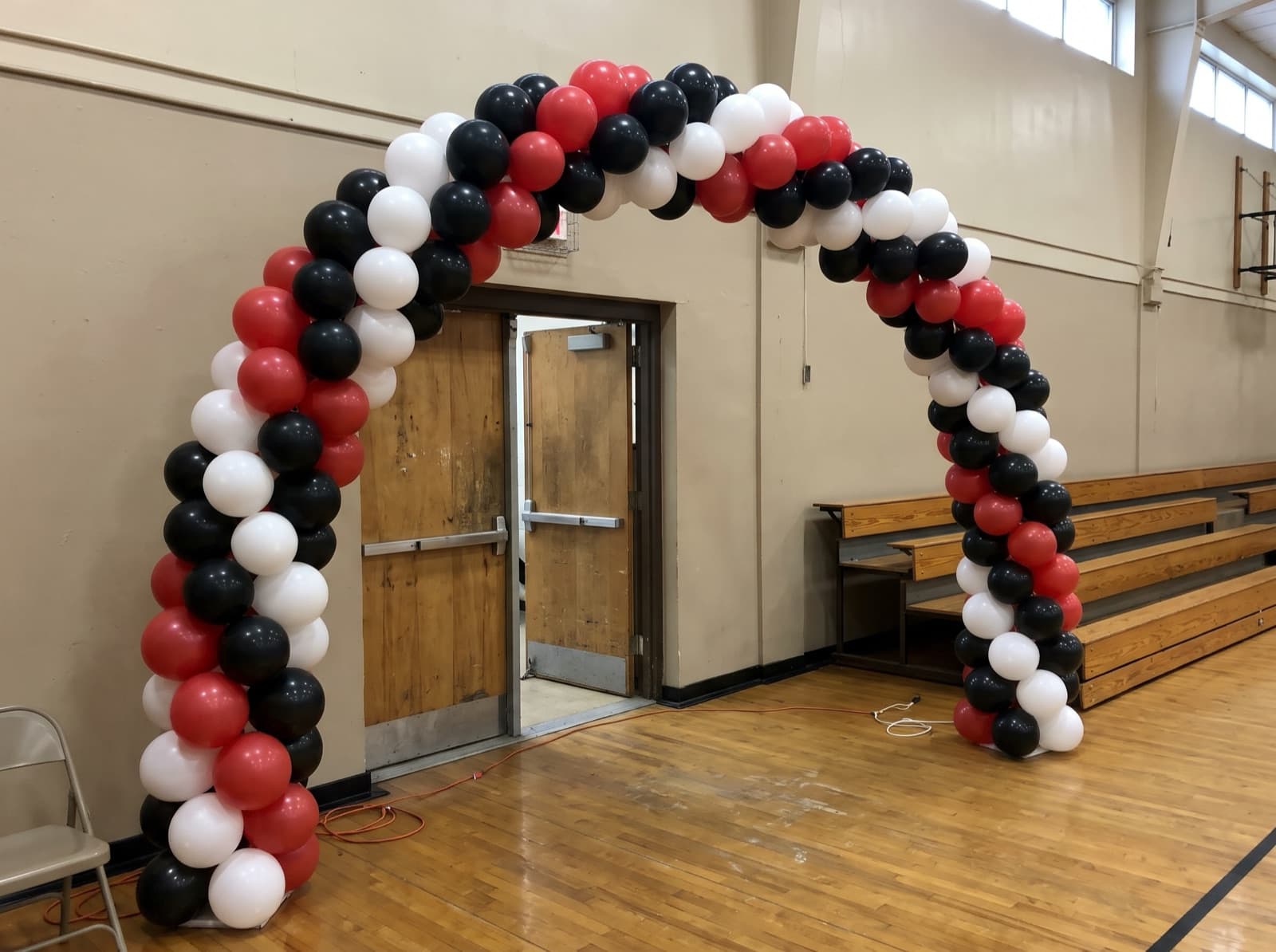 Spiral balloon arch in red and black over a gym entrance