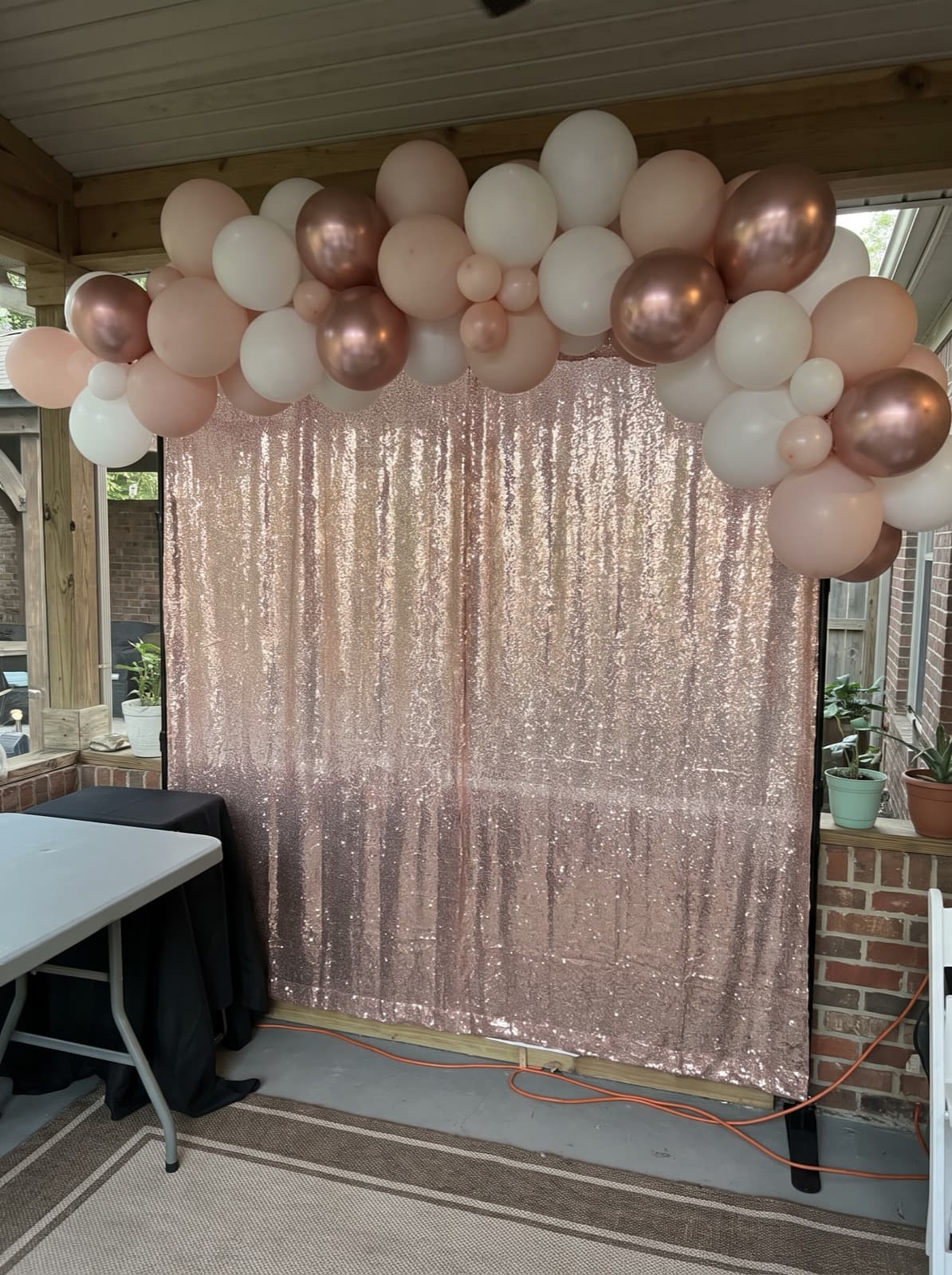 Rose gold shimmer wall backdrop with a balloon garland