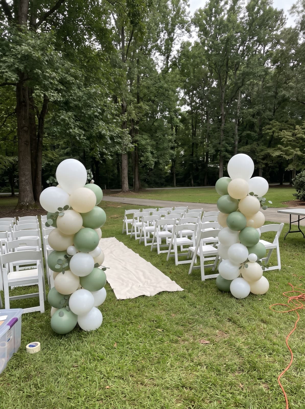 Organic balloon columns lining an outdoor wedding aisle